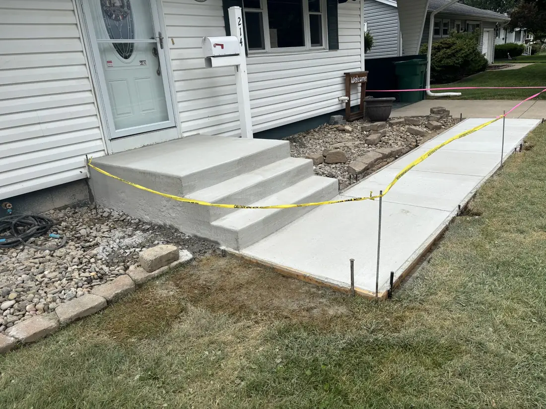 Freshly placed concrete sidewalk and entry steps shown together during curing