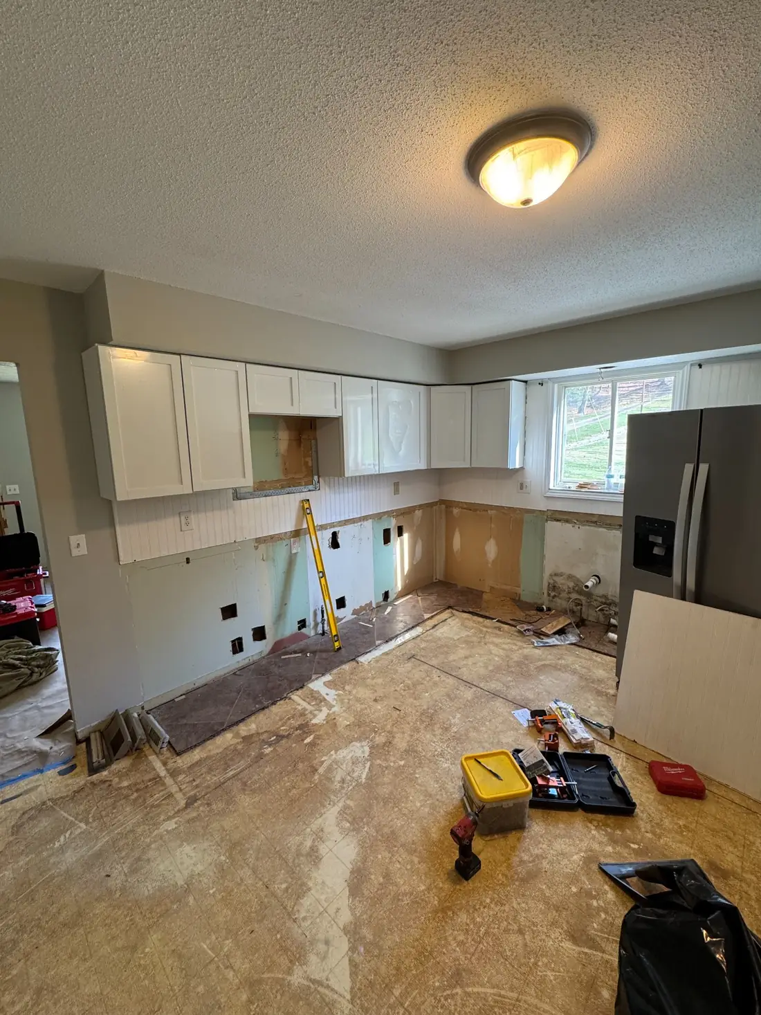 Kitchen during demolition with lower cabinets, counters, and flooring removed