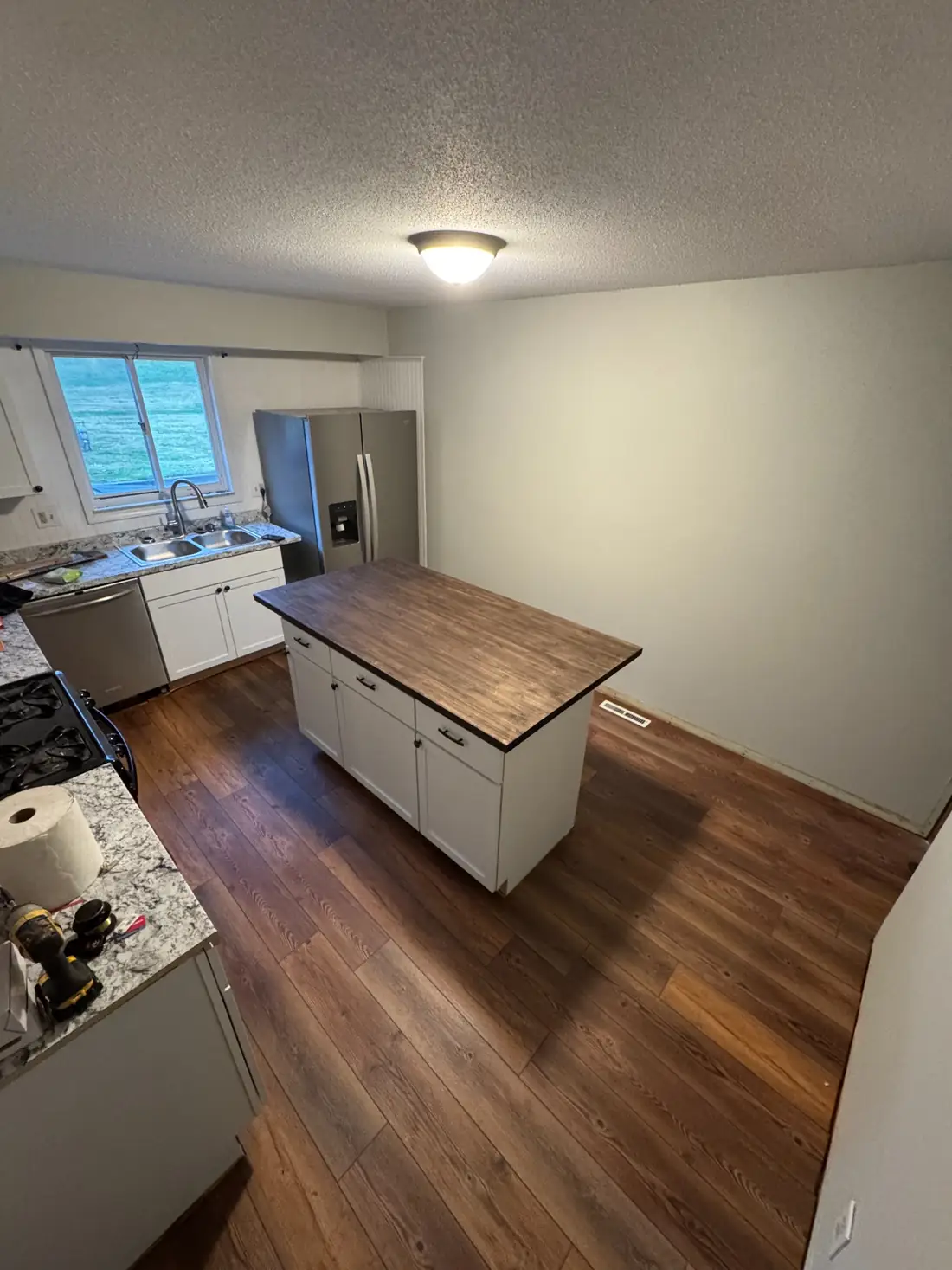 Kitchen during installation with white cabinetry, counters, island, and new flooring in progress